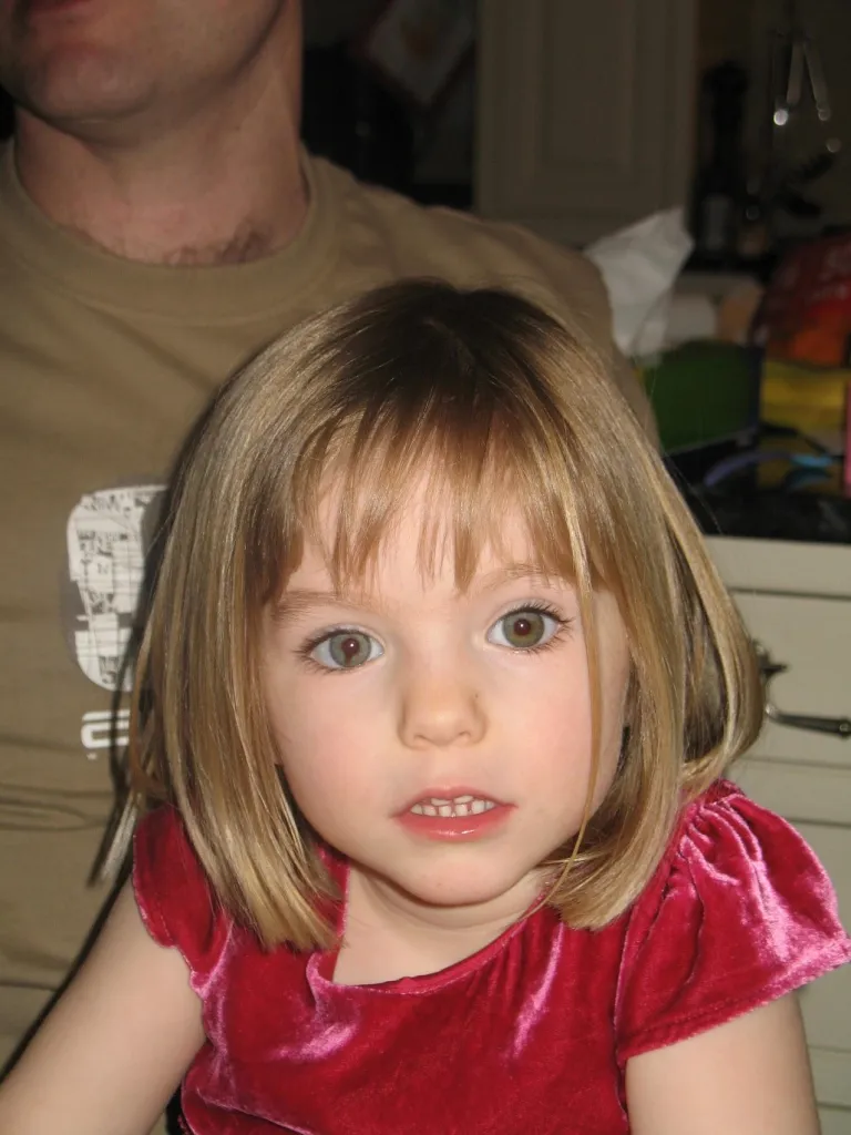 Madeleine McCann, a young girl with blonde hair and hazel eyes, wearing a red velvet top.