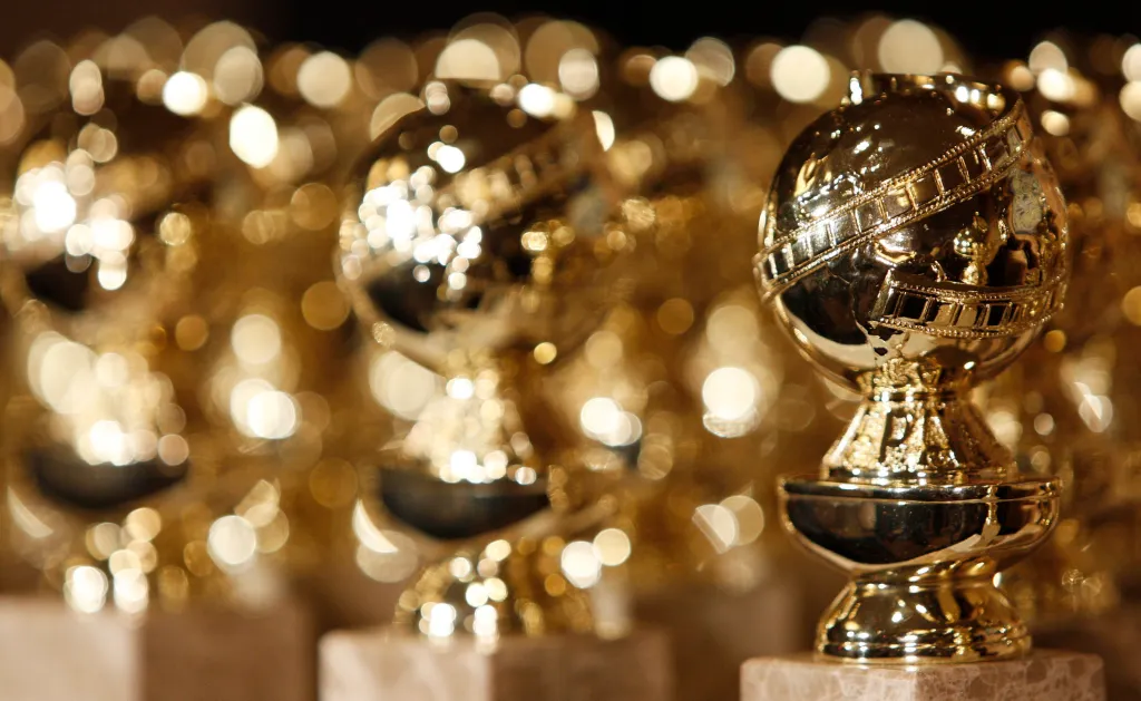 Golden Globe statuettes with bokeh lights in the background.