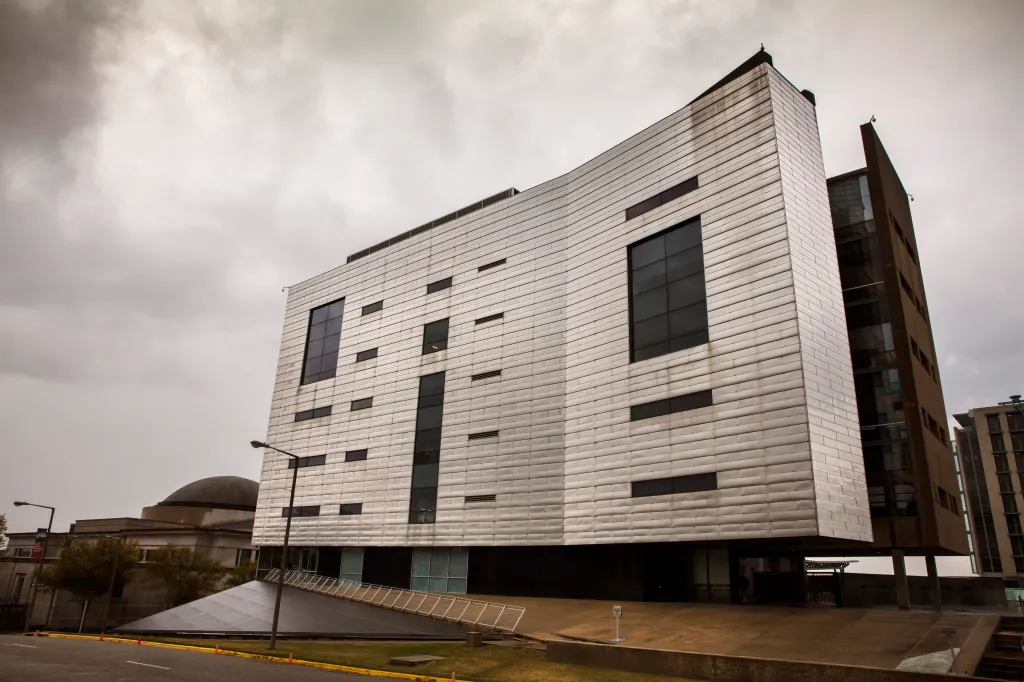 The Southern Poverty Law Center building, a modern structure with metallic paneling and dark windows, against a cloudy sky in Montgomery, Alabama.