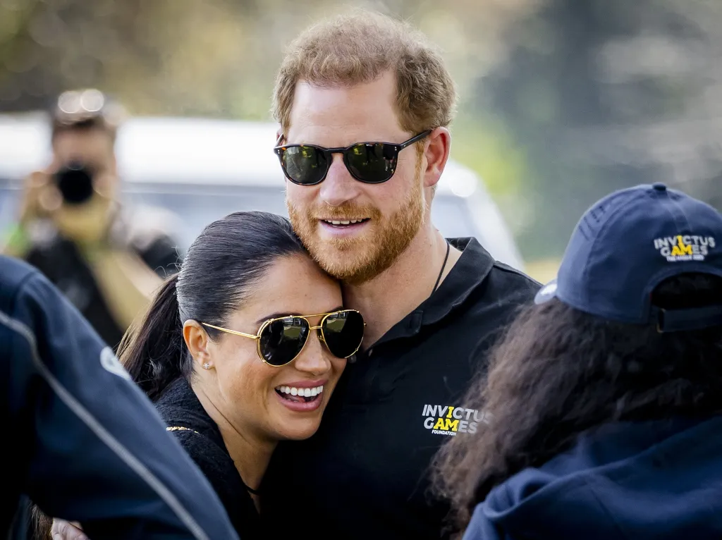 Meghan Markle smiles, leaning her head on Prince Harry's shoulder at the Invictus Games.