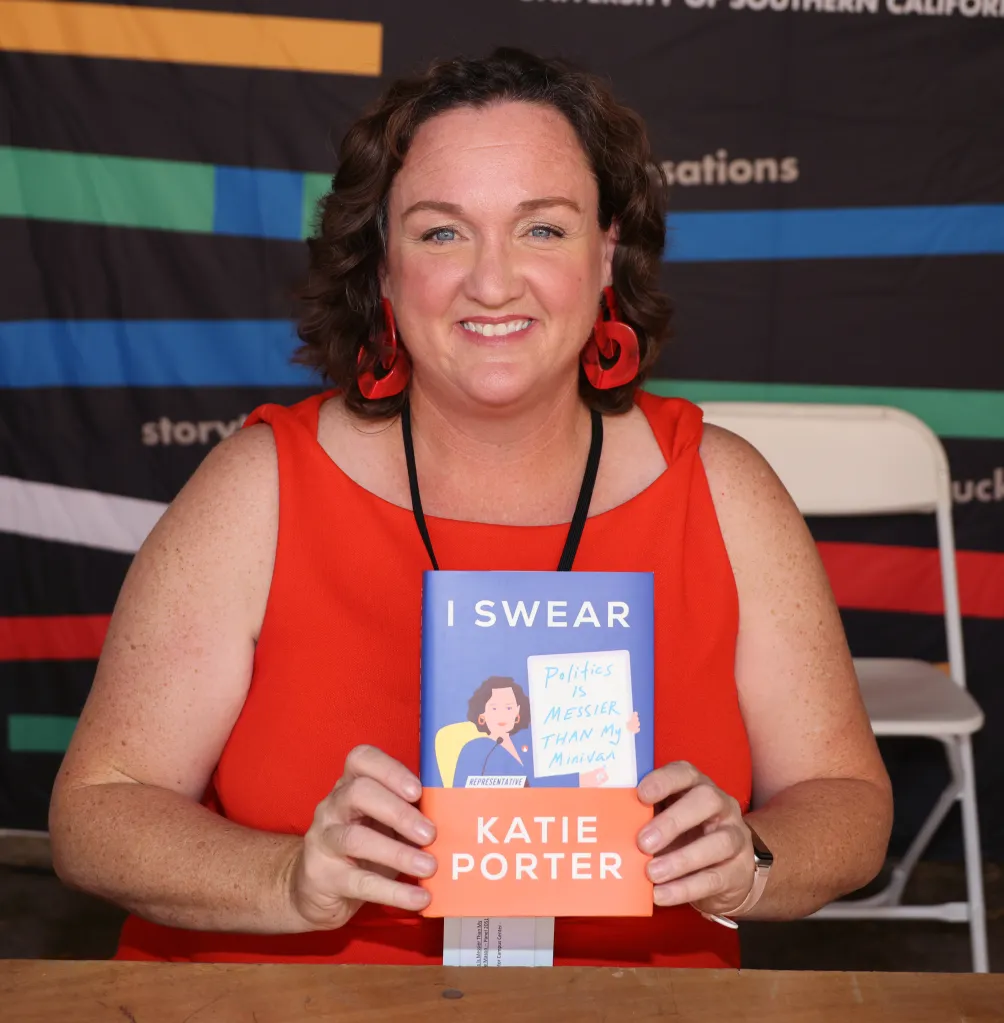 Katie Porter holds up her book, "I Swear: Politics Is Messier Than My Minivan" at the 2023 Los Angeles Times Festival of Books.