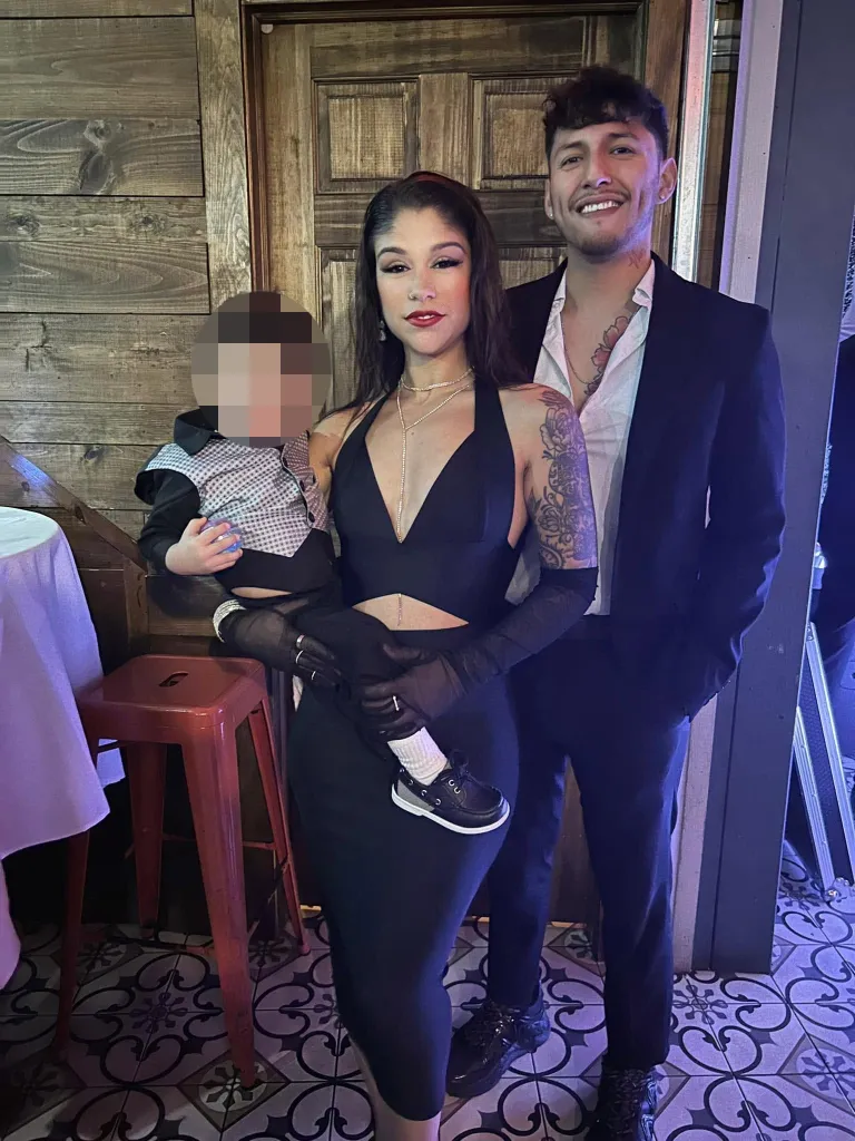 Jesher Rivera-Barreto holding her 4-year-old son, with a man standing beside them.