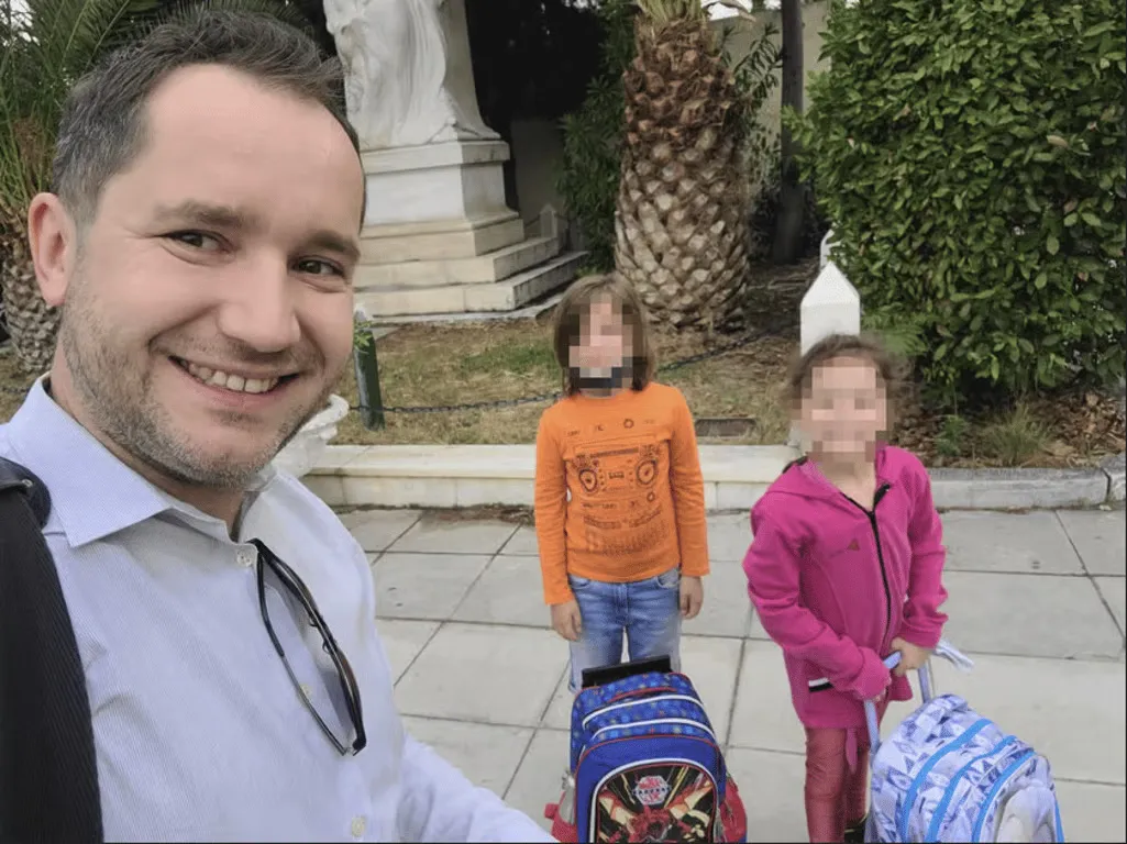 Przemek Jeziorski smiling with his two young children, whose faces are blurred.