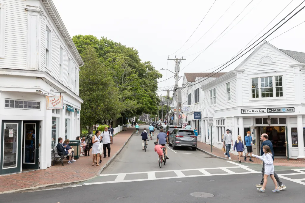 A street scene in Edgartown, Massachusetts, showing pedestrians, cyclists, and storefronts.