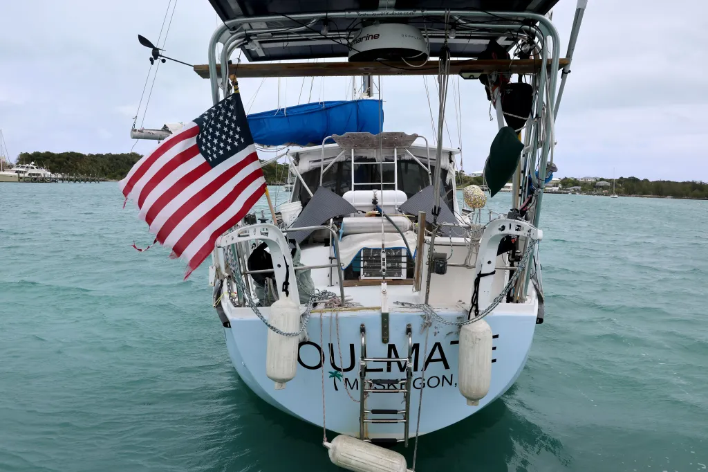 Stern view of the boat "Soulmate" with an American flag attached, floating in calm turquoise water.