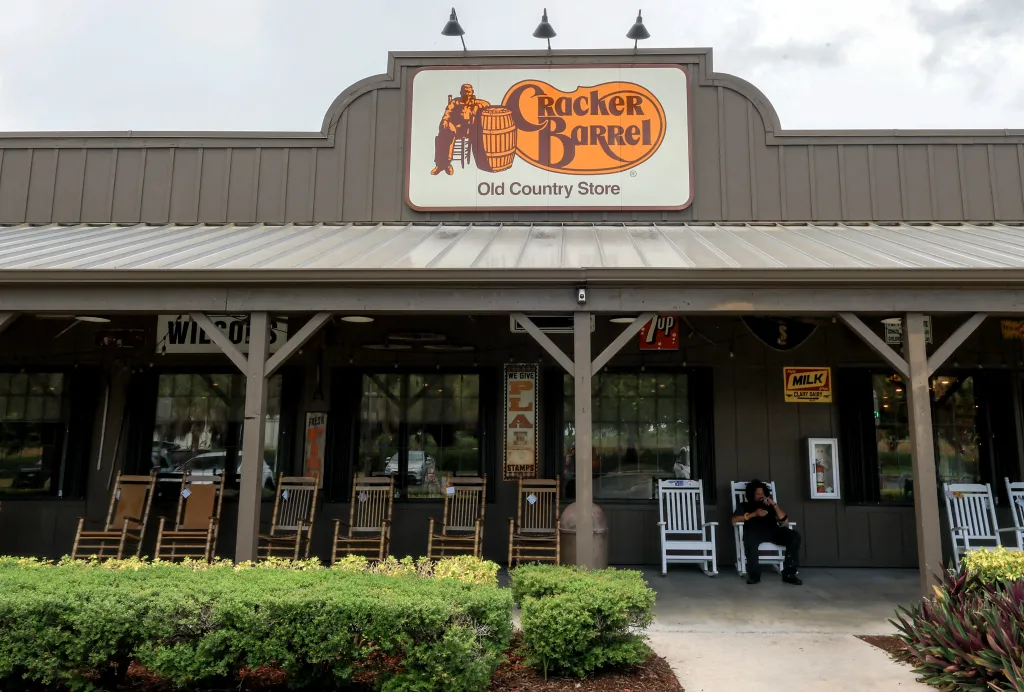 The old Cracker Barrel logo featuring a man sitting next to a barrel and the phrase "old country store" hangs on the outside of a restaurant in Homestead, Florida.