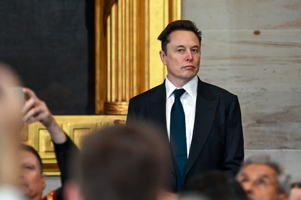 Elon Musk in a dark suit and tie at an event.
