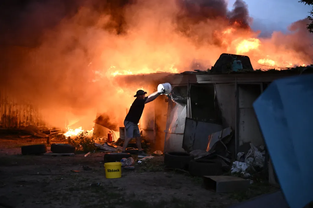 A local resident extinguishes burning garages in Kyiv following a Russian missile strike.