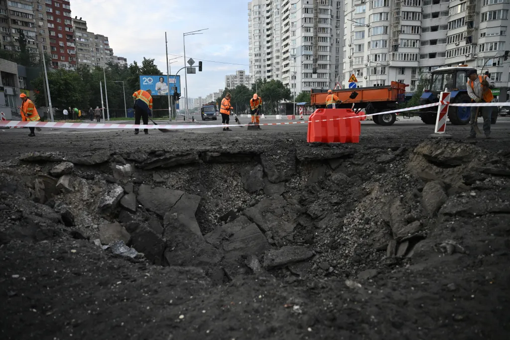 Communal workers clean debris around a crater in the street in Kyiv.