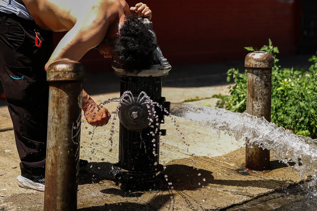 A man cools off at a fire hydrant in Hamilton Heights, Manhattan.