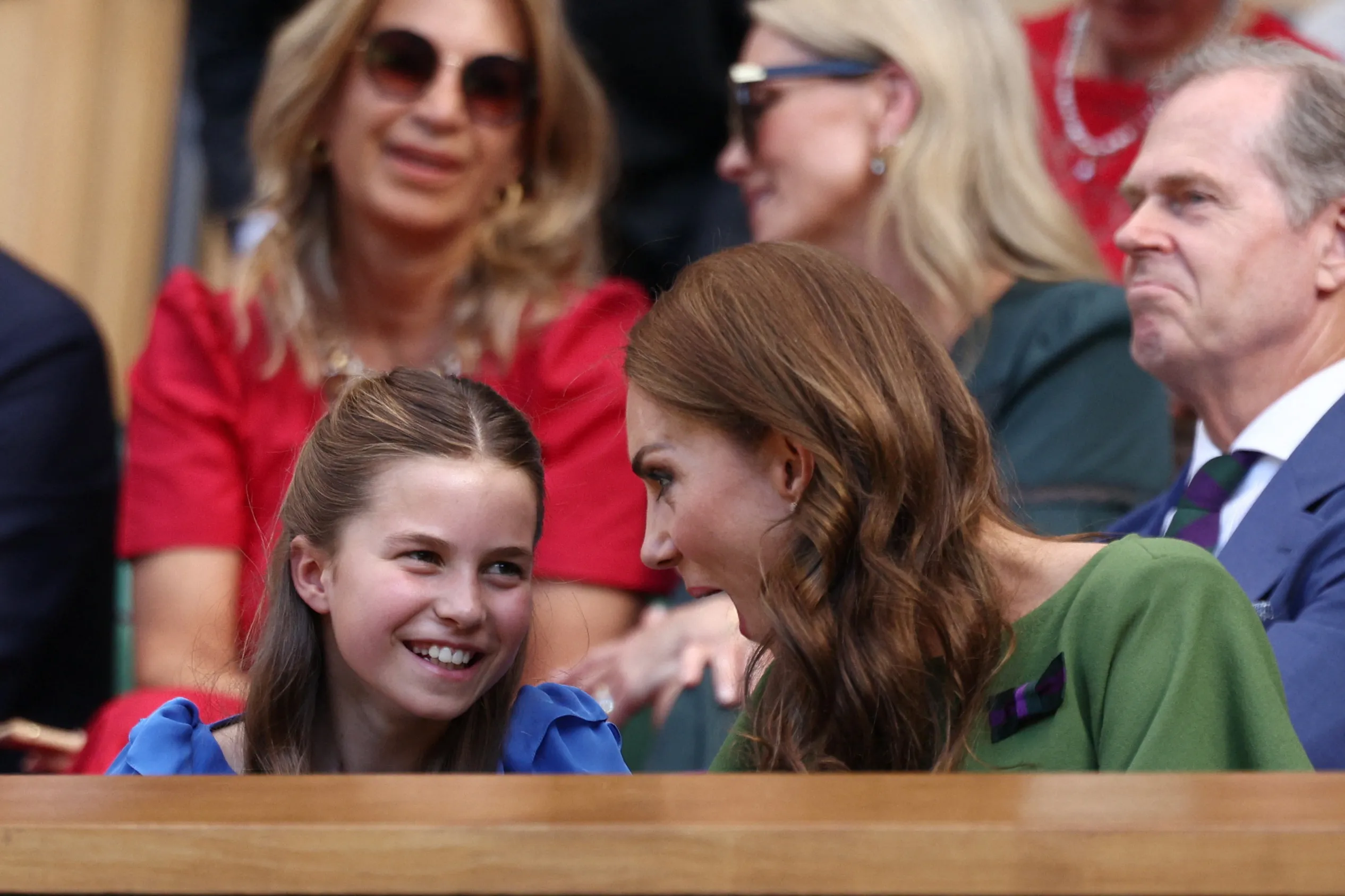 Catherine, Princess of Wales, in a green dress and Princess Charlotte in a blue dress, watch the Wimbledon final.