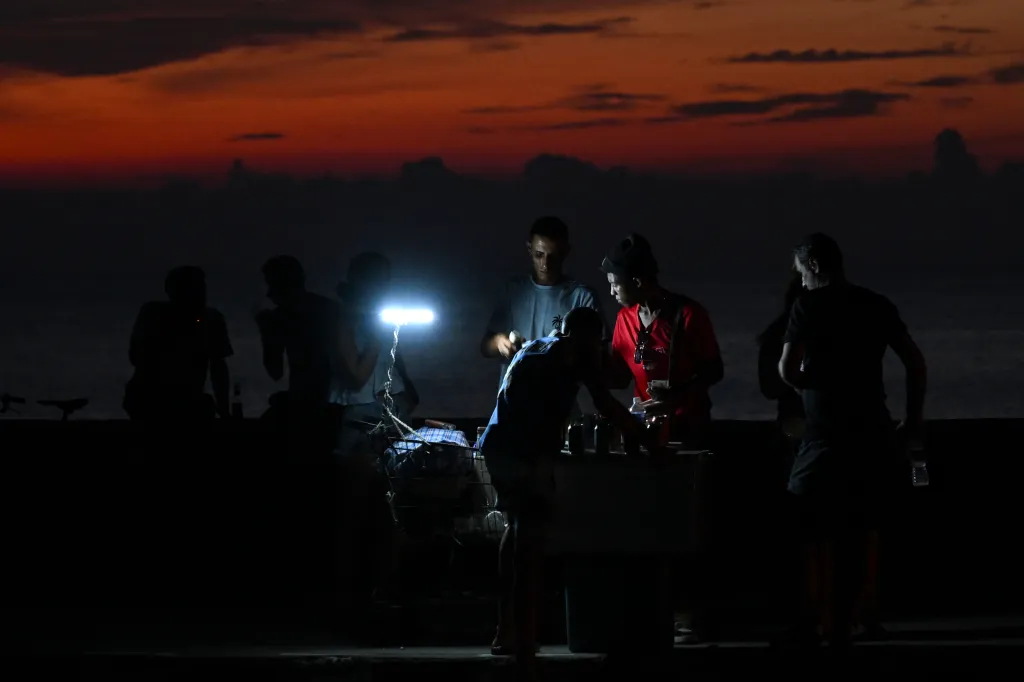 People on the Malecon illuminated by a small light during a nationwide blackout in Havana.