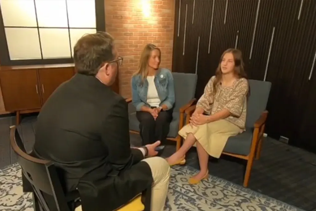 Three people, a man, a woman, and a girl, sit in chairs in a room with brick walls.