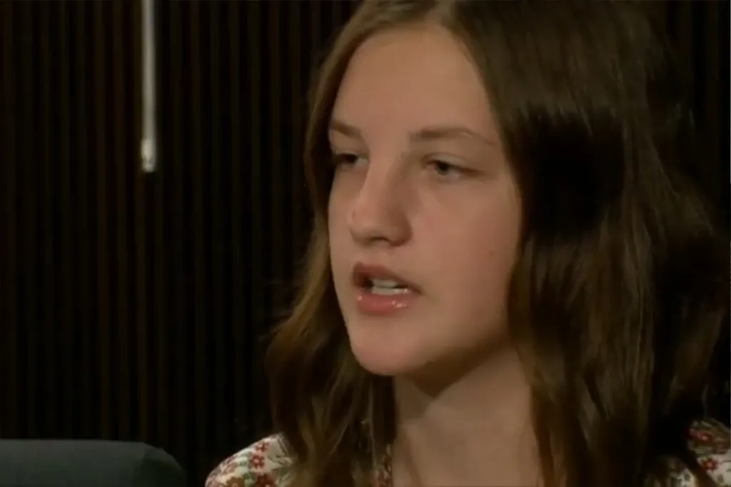 A young woman with brown hair and a floral top speaking.
