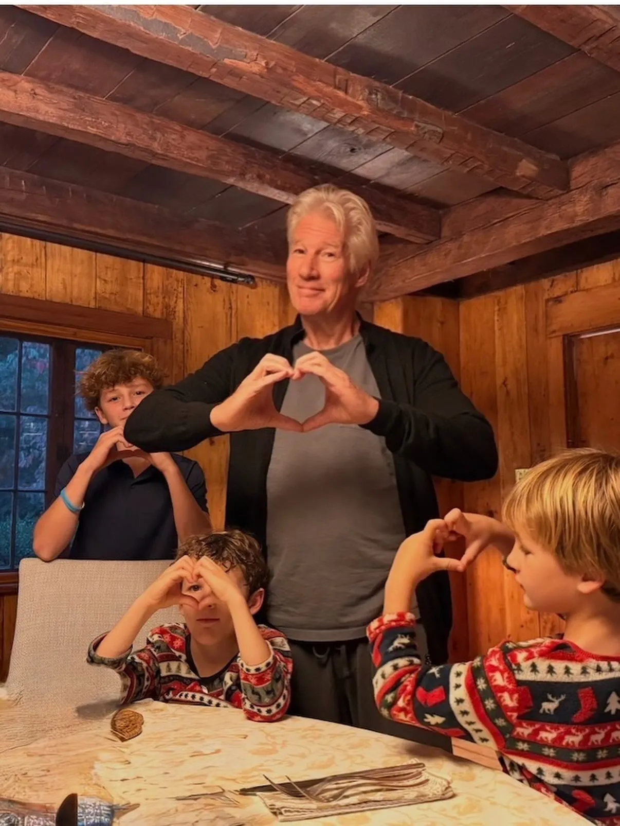 Richard Gere and three children making heart shapes with their hands.