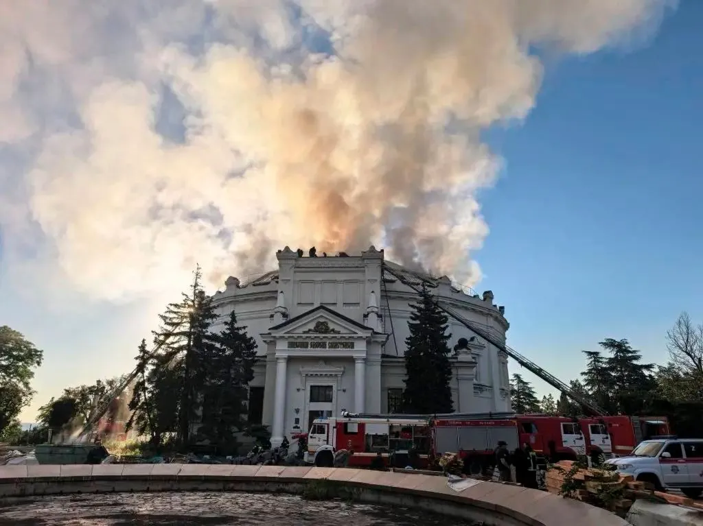 Firefighters battle a fire on the roof of the "Defense of Sevastopol 1854-1855" Panorama building, with thick smoke rising into the sky.