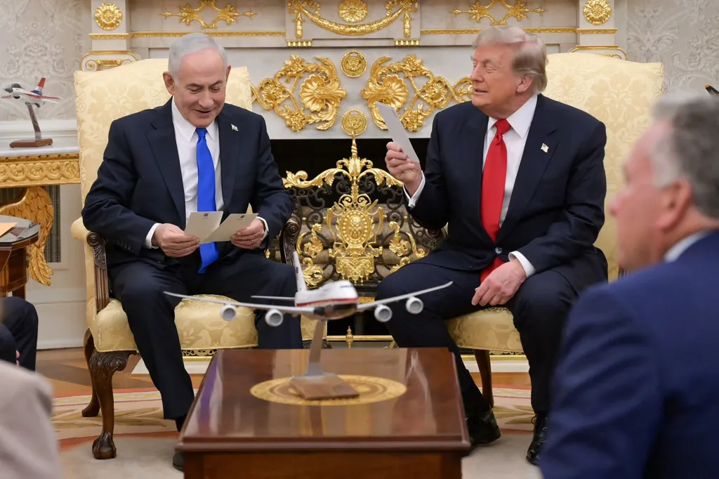 Benjamin Netanyahu and Donald Trump sit in the Oval Office, both smiling and holding papers.