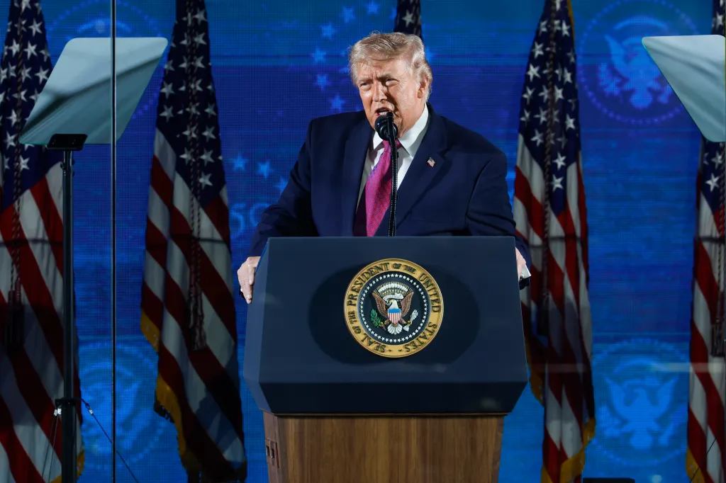 President Donald Trump speaks at a podium with the Seal of the President of the United States, flanked by American flags.