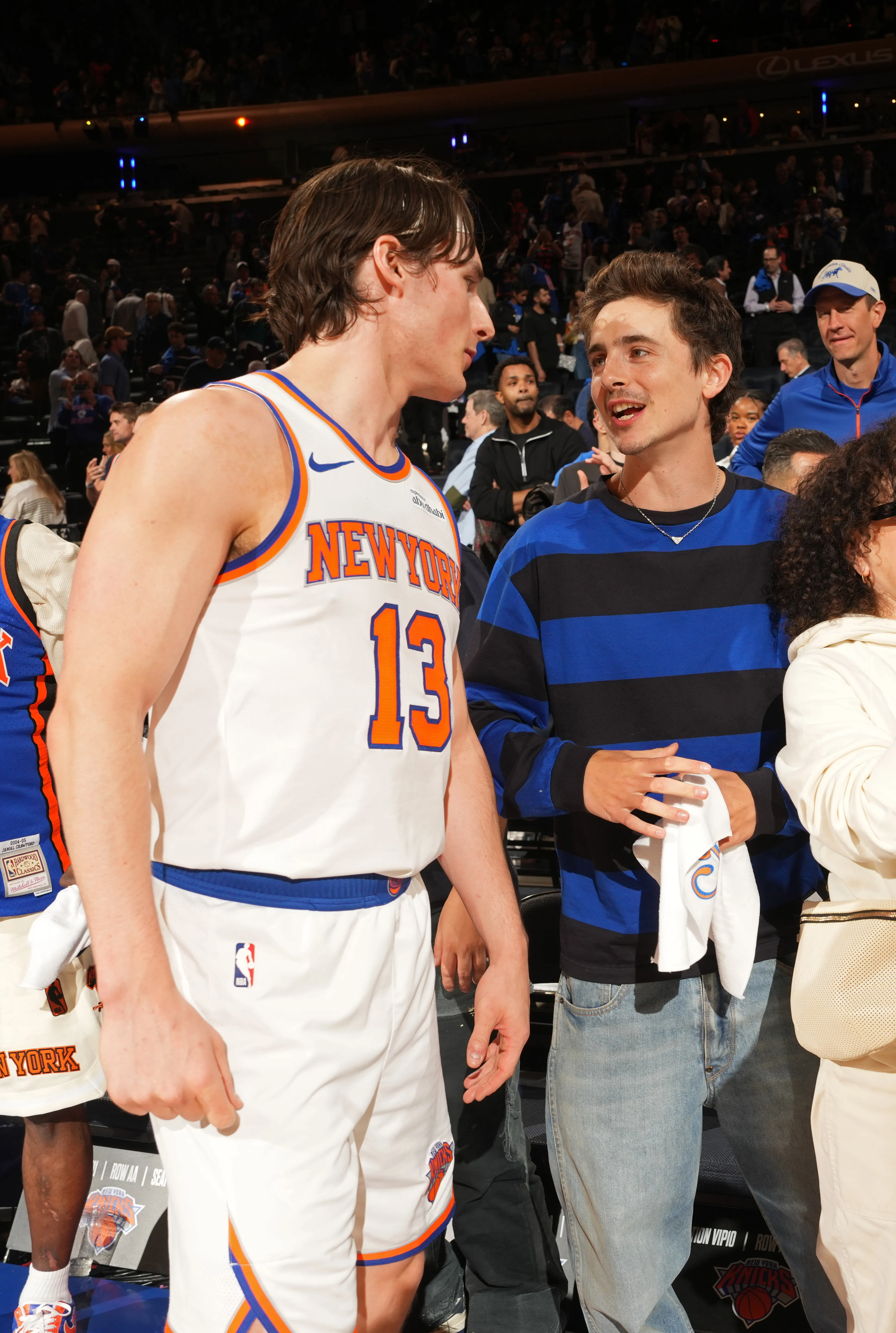 Tyler Kolek of the New York Knicks and Timothee Chalamet talk during a basketball game.