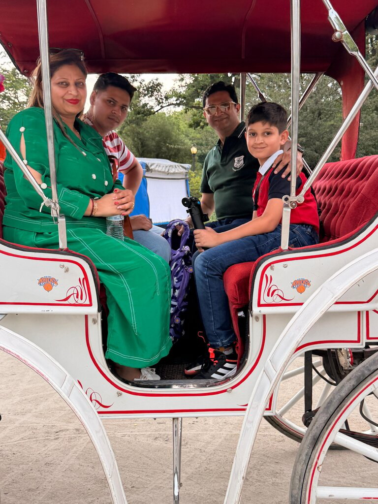 Romanch Mahajan, 18, and his family, Priya, Deepak, and Maanik, pose in a Central Park horse carriage.