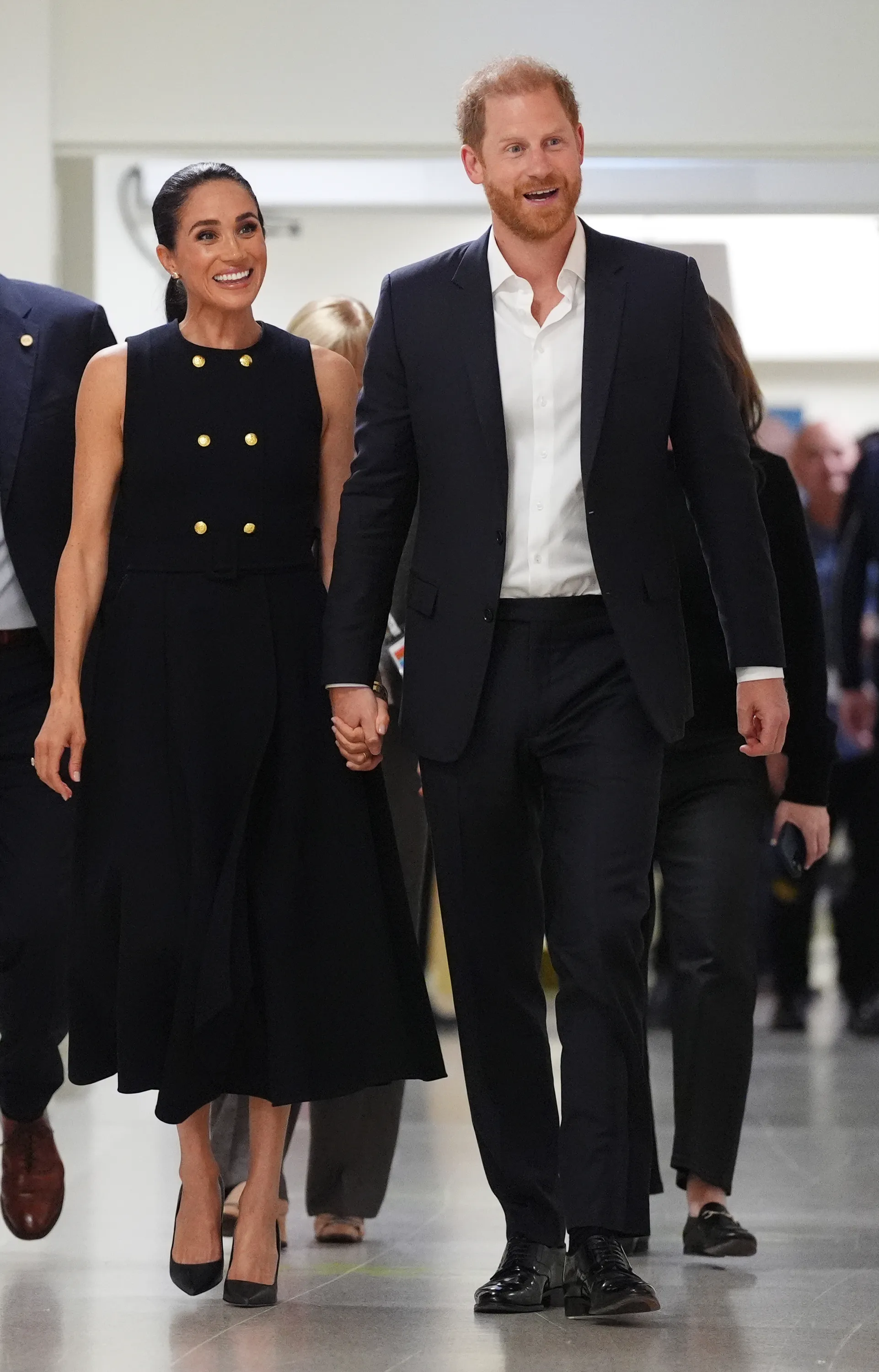 Meghan, Duchess of Sussex, and Prince Harry, Duke of Sussex, walking hand-in-hand.