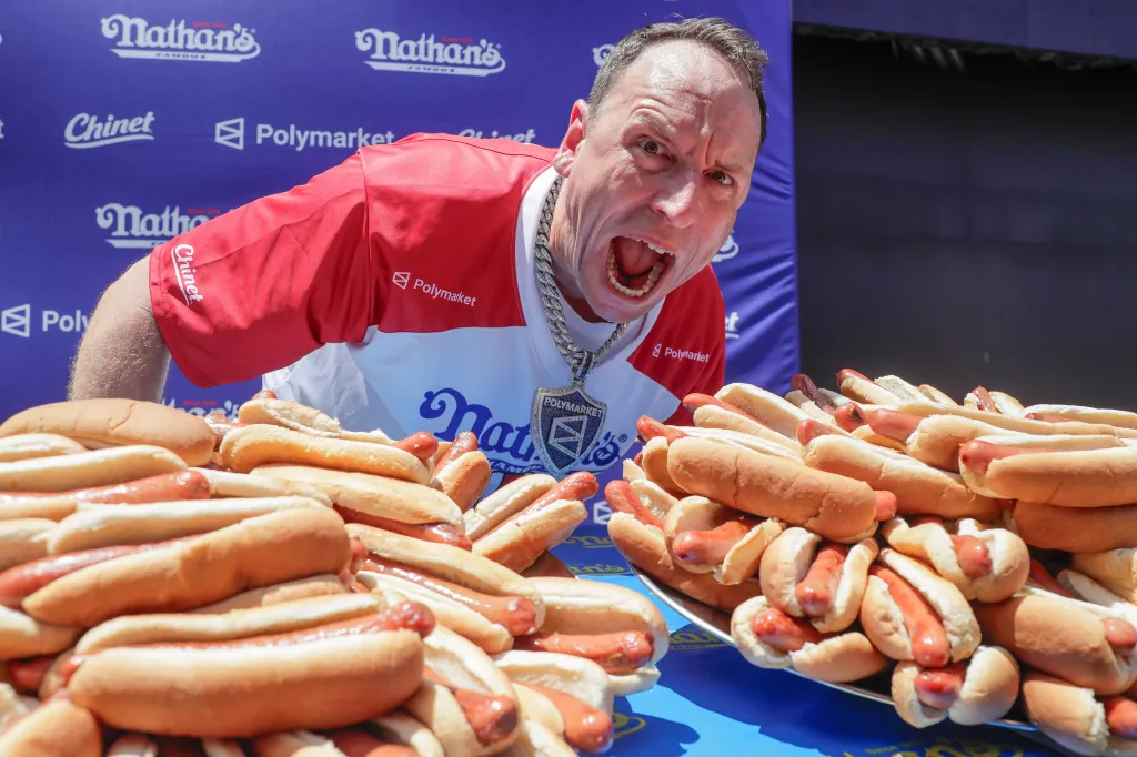 Joey Chestnut with his mouth wide open, surrounded by hot dogs, at the Nathan's Famous Fourth of July International Hot Dog Eating Contest weigh-in.