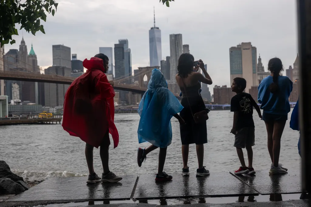People in rain ponchos look at the New York City skyline from Dumbo, Brooklyn.
