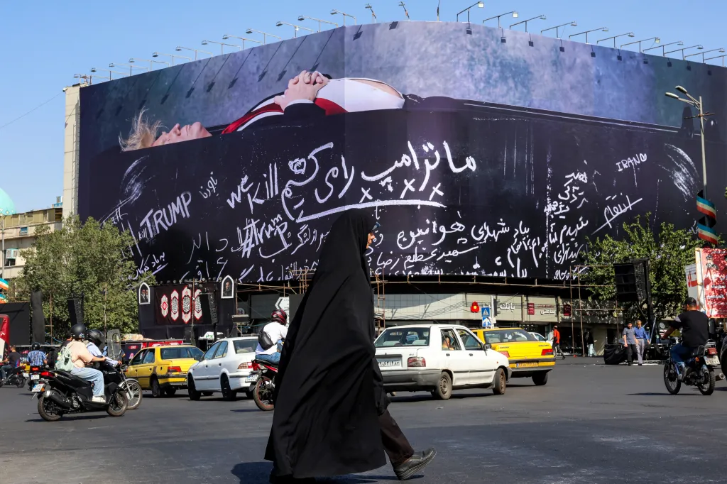 A woman walks past a giant anti-US billboard with a picture of Donald Trump in a coffin and text in Persian reading "We Kill Trump".
