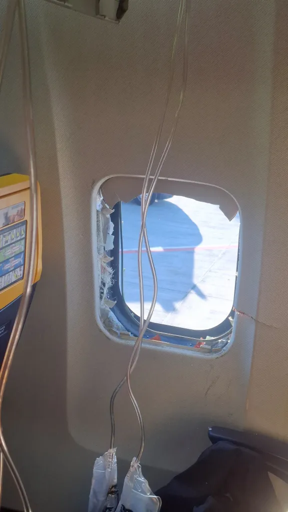 A broken aircraft window with the exterior visible, following an emergency landing.