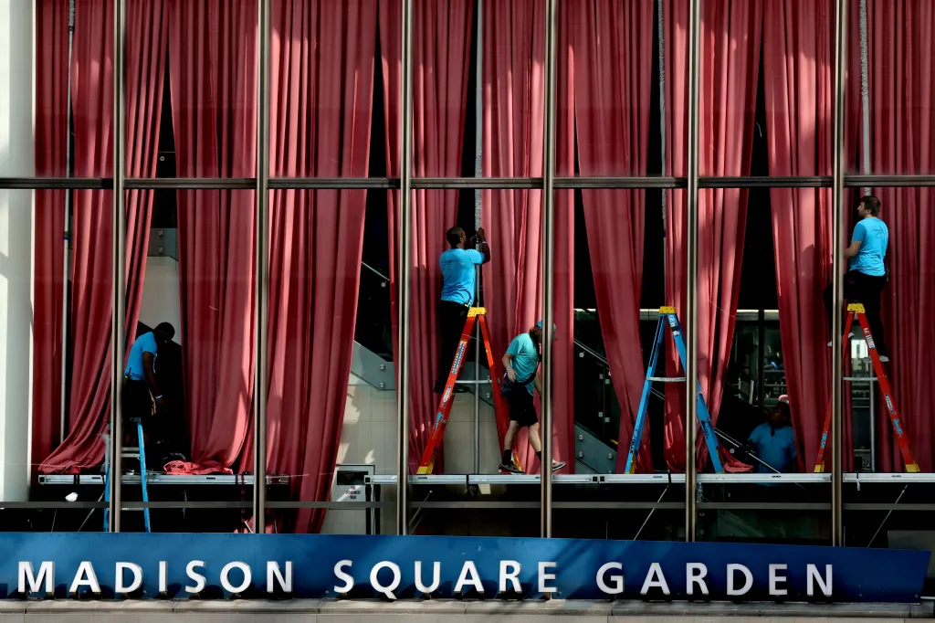 Workers hang red drapes over the windows of Madison Square Garden to provide privacy for an event.