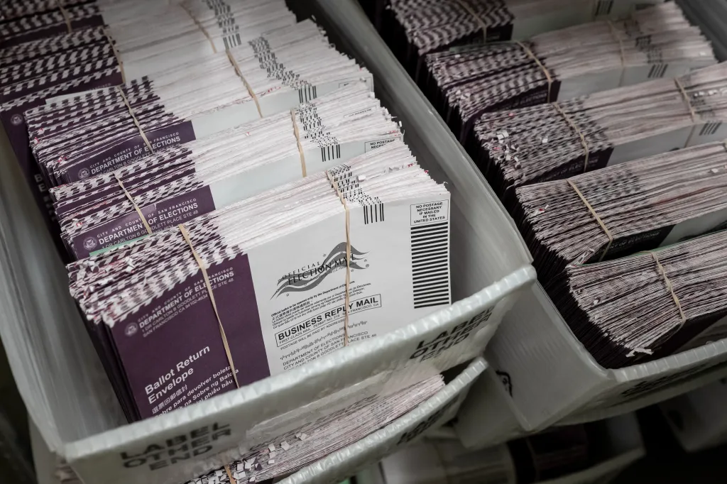 Stacks of mail-in ballots in trays.