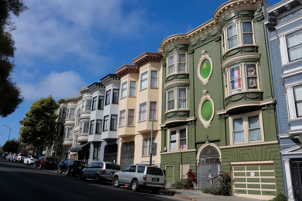 A street scene of San Francisco homes in North Beach, with several cars parked along the curb.