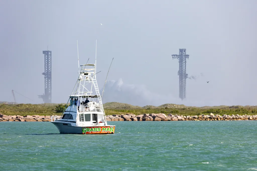 A boat passes in front of the viewing area for the SpaceX launch as smoke shoots out from the launch pad near South Padre Island, Texas.