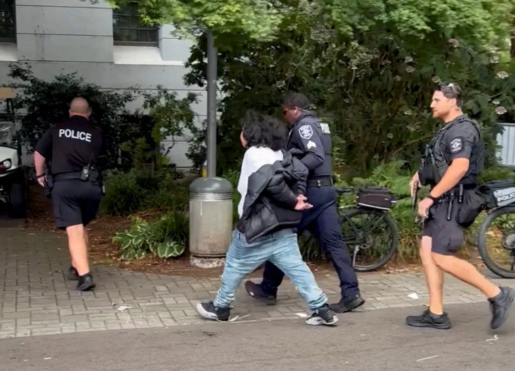 Police officers detaining a man near Seattle Center following a shooting incident.