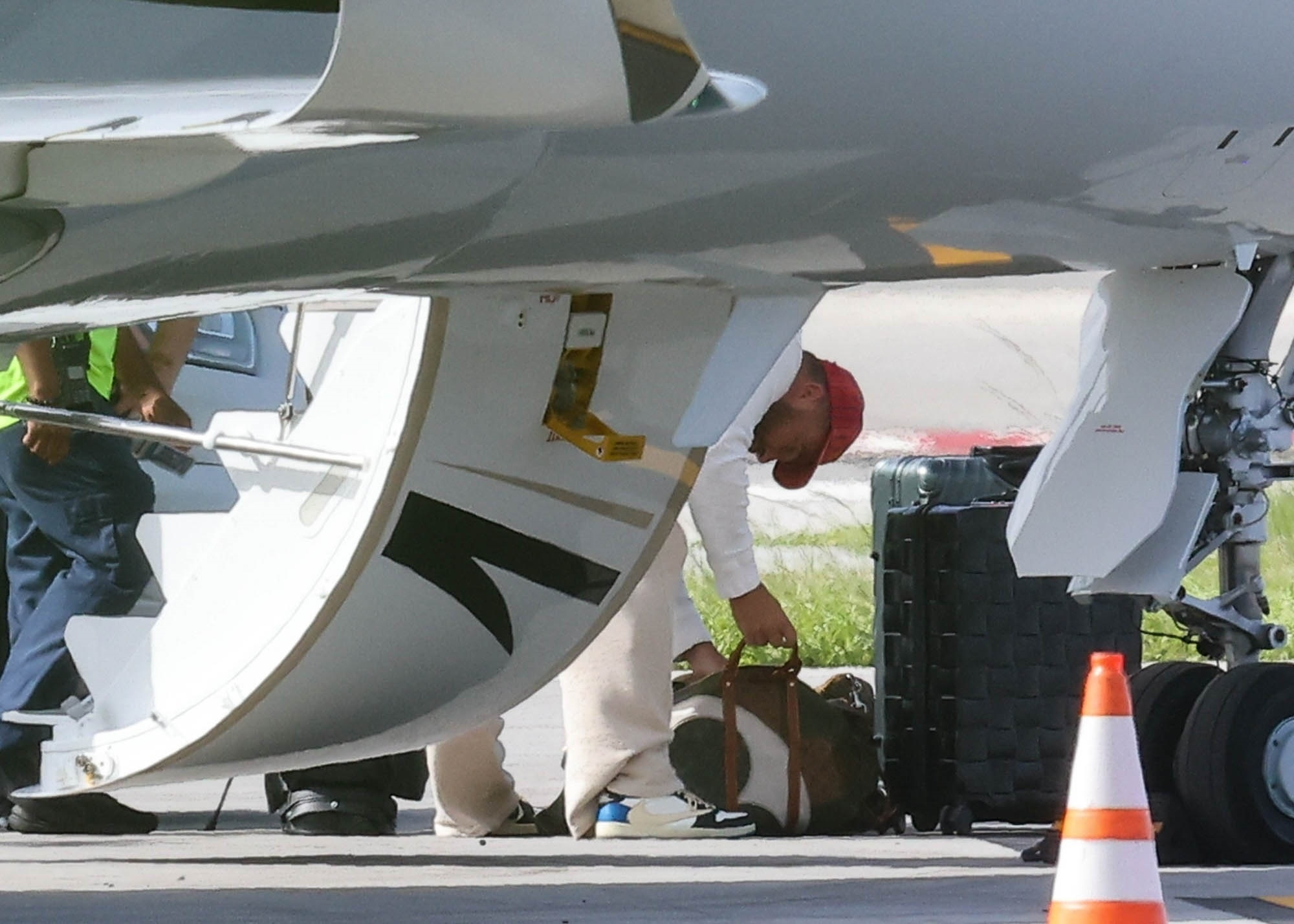 Travis Kelce retrieves luggage from an airplane.