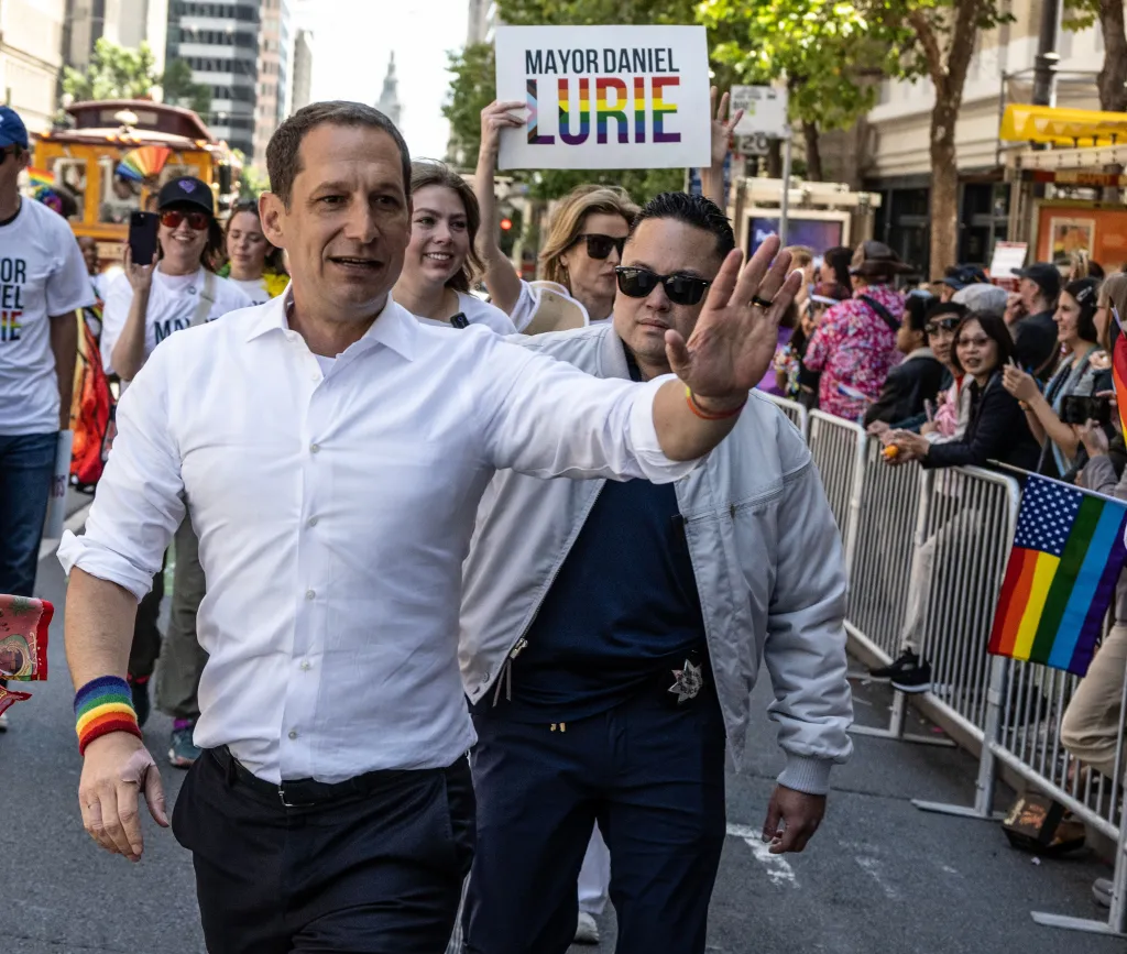 Mayor Daniel Lurie waves to crowds during an LGBTQ Pride Parade.