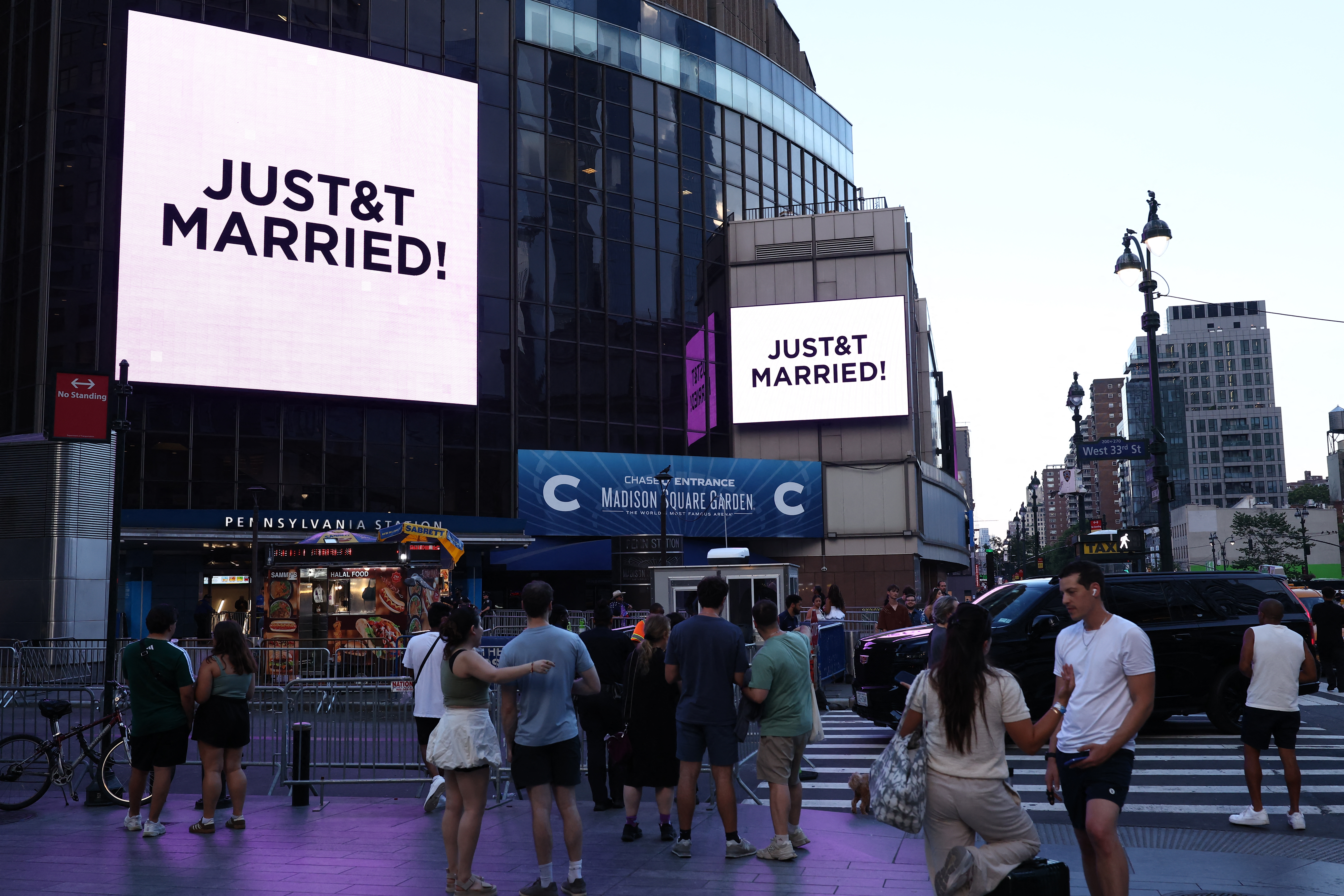 People gather in front of Madison Square Garden with signs reading "JUST&T MARRIED!".