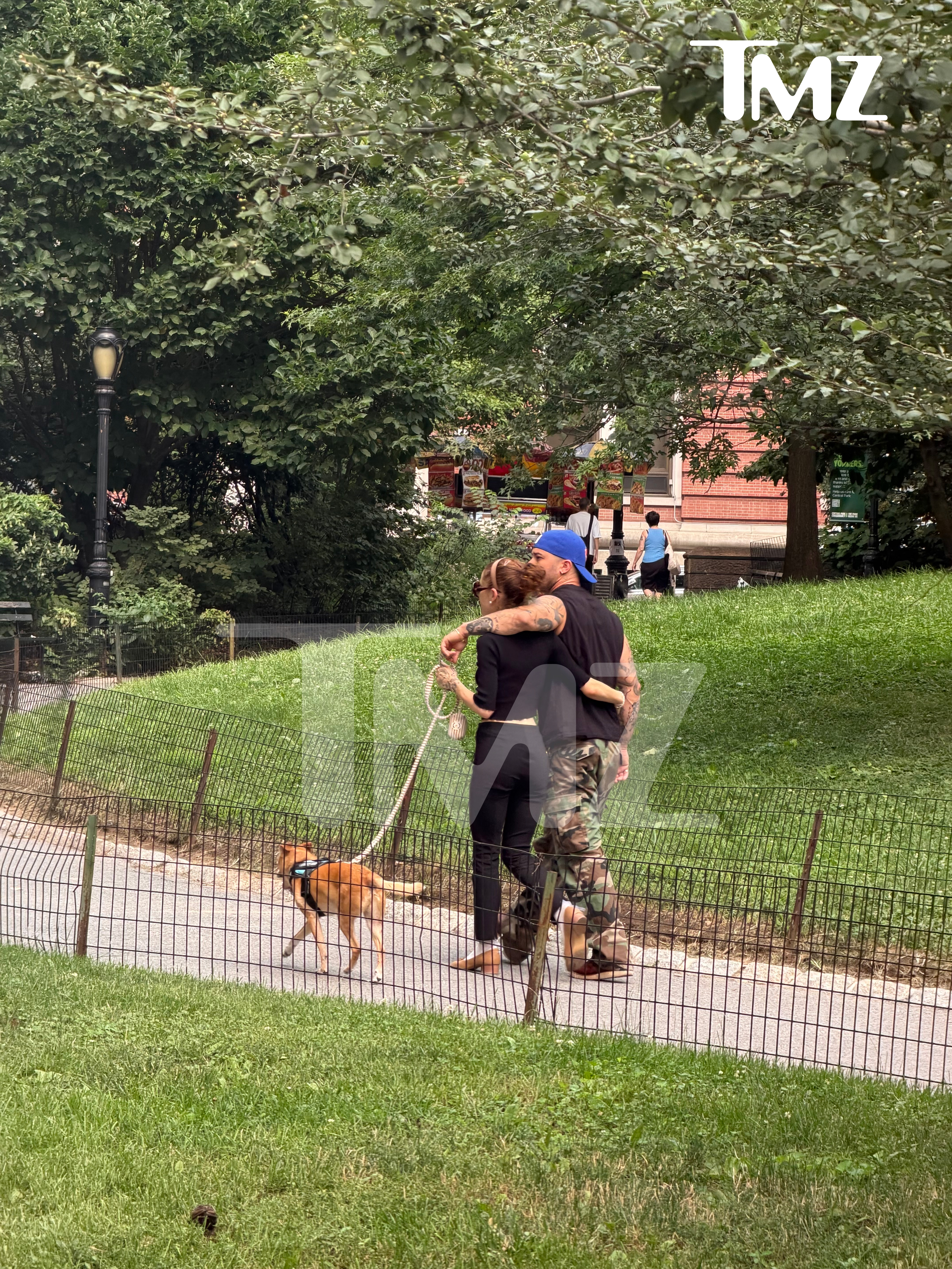 Ariana Grande and Ricky Alvarez walking a dog in a park.