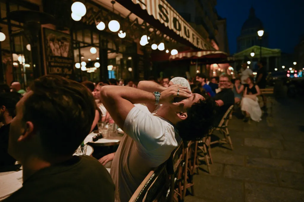 A French football fan reacts with hands over his eyes while watching a match at a cafe in Paris.