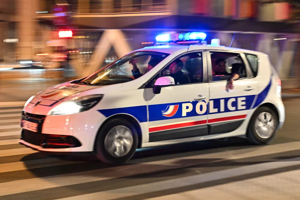 French police car with flashing lights driving at night.