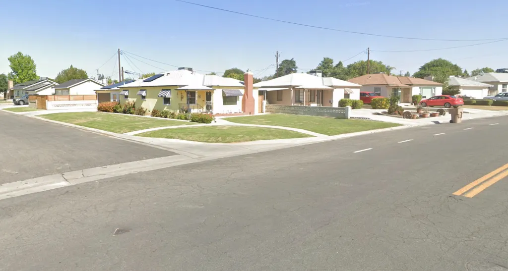 The 2700 block of Olympic Drive in Oildale, California, featuring single-story houses with manicured lawns and cars parked in driveways, viewed from the street.