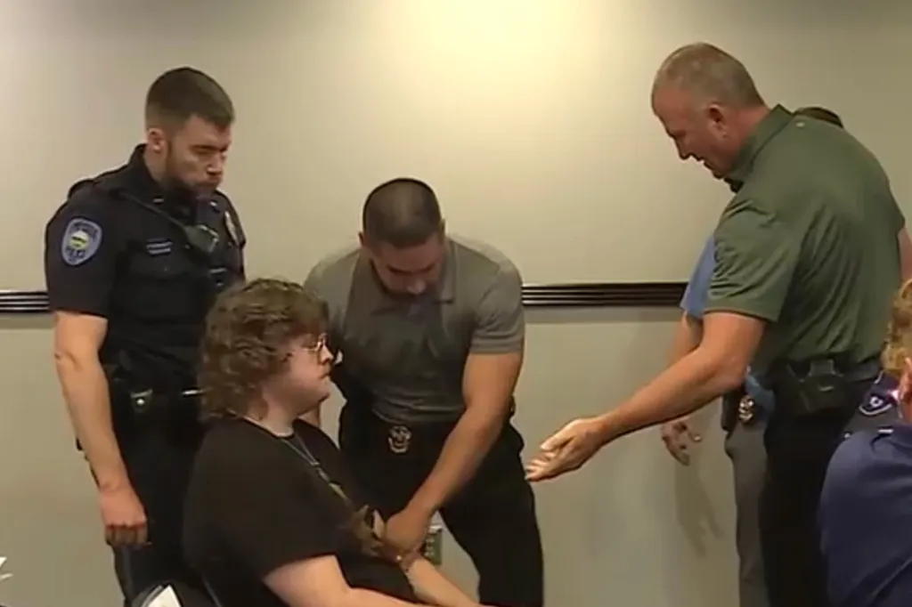 Lux Claridge is surrounded by several law enforcement agents after clapping during the Emporia City Commission meeting on July 22, 2026.