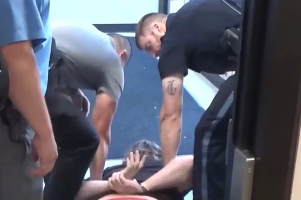 Three police officers arresting a man, Lux Claridge, on the ground, placing his hands behind his back.