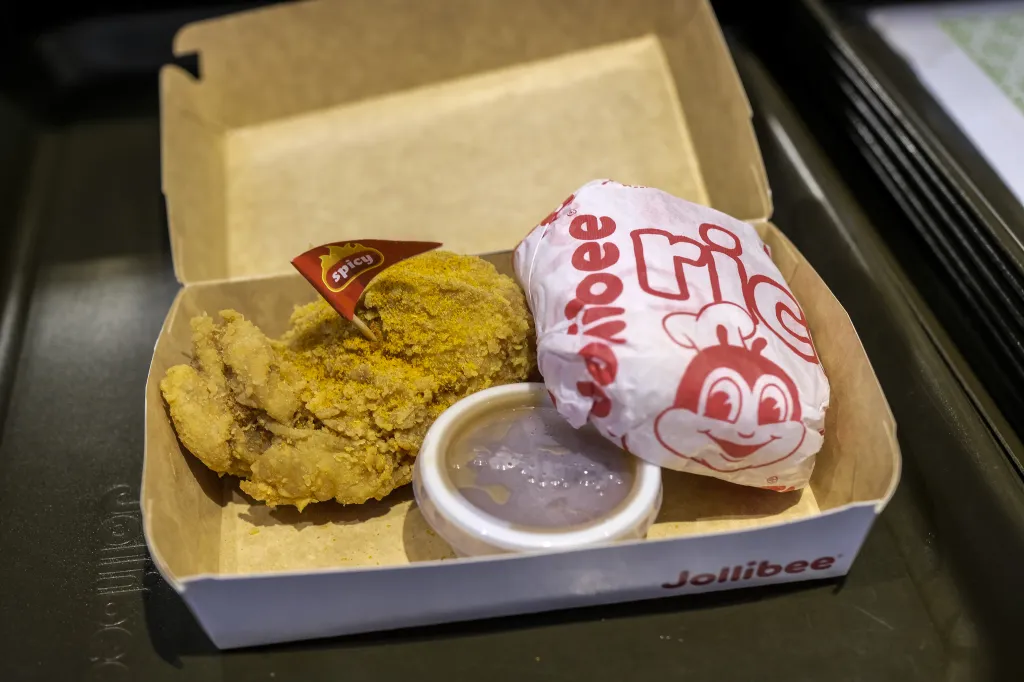 A Jollibee fried chicken meal with rice, sauce, and a "spicy" flag in a cardboard box.