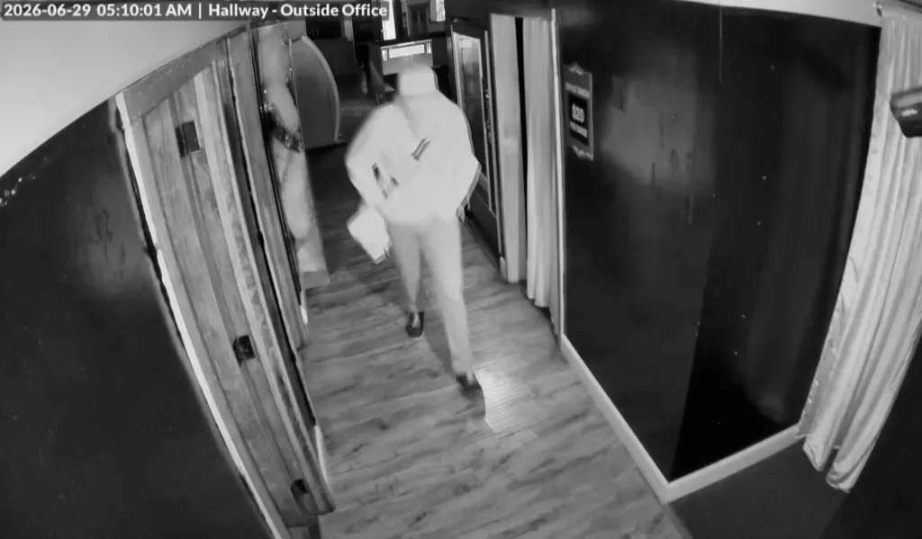 Surveillance footage of a thief walking down a hallway carrying a bag of stolen money.