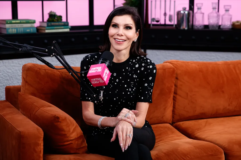 Heather Dubrow smiling while sitting on an orange couch next to a "Virtual Reali-Tea" microphone.