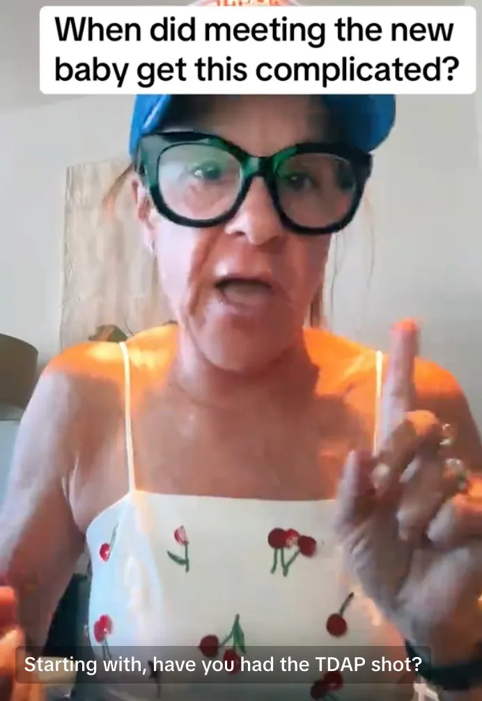 A woman in a cherry-print top, glasses, and a hat asks, "When did meeting the new baby get this complicated? Starting with, have you had the TDAP shot?"