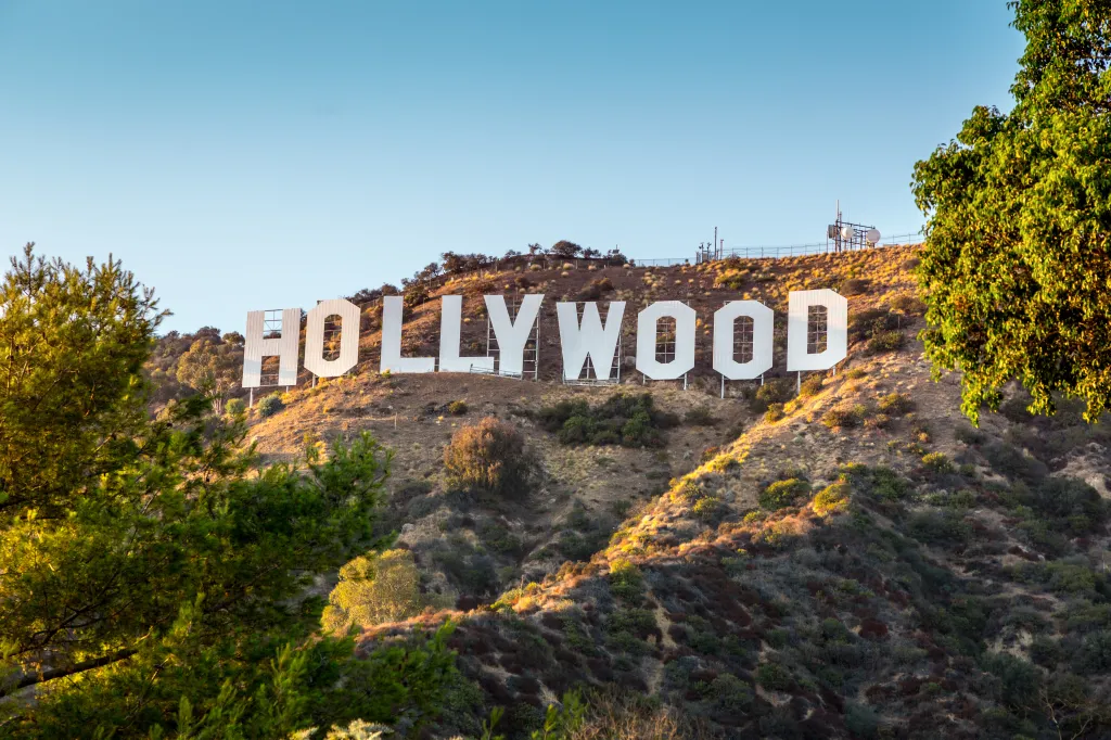 The Hollywood sign on a hill, with trees in the foreground.
