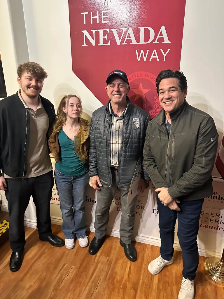 Dean Cain Lombardo standing with three other people in front of a sign that reads "The Nevada Way."