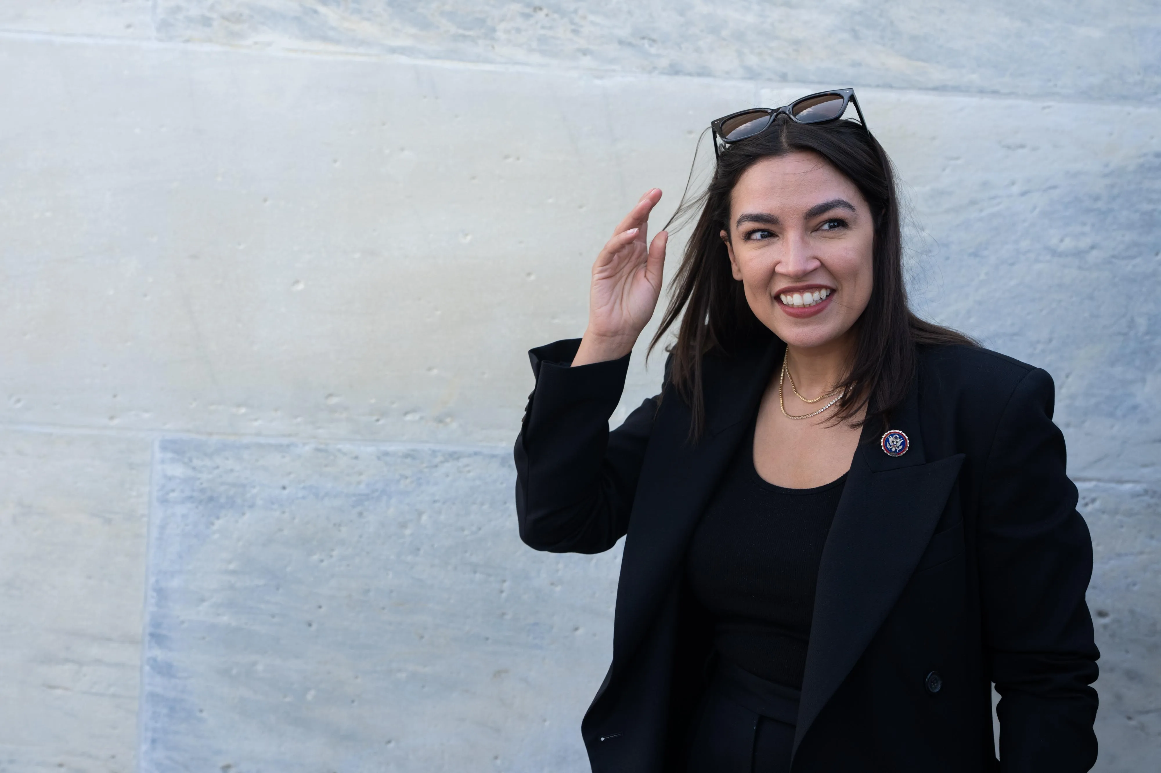 alexandria ocasio-cortez smiling in front of a blue background alexandria ocasio-cortez smiling in front of a blue background